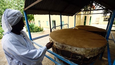 A man stands next to drums.