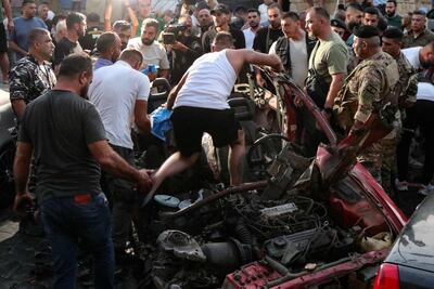 People and security forces check the wreckage of a car, reportedly struck by an Israeli drone attack in the main square of the southern Lebanese town of Marjayoun on Wednesday. AFP
