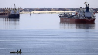 A fisherman travels on a boat with his family in front of a Voyager K bulk carrier ship, left, and a Tokyo Marine tanker, right, in the Suez Canal. Amr Abdallah Dalsh / Reuters
