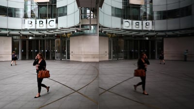 A woman is reflected as she passes the BBC's Broadcasting House in London