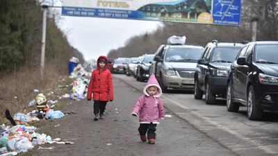 Ukrainian children walk past a line of cars heading towards the Polish border. AP