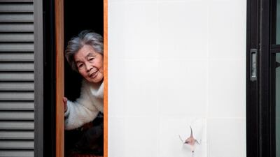 In this picture taken on January 16, 2018, Kimiko Nishimoto poses next to a picture of her on the sliding window of her house in the western Japanese city of Kumamoto. The madcap Japanese great-grandmother armed with a camera and an appetite for mischief has shot to fame for taking side-splitting selfies -- many of which appear to put her in harm's way. / AFP PHOTO / Behrouz MEHRI / TO GO WITH Japan-lifestyle-photography-offbeat-senior-citizens,FEATURE by Alistair HIMMER