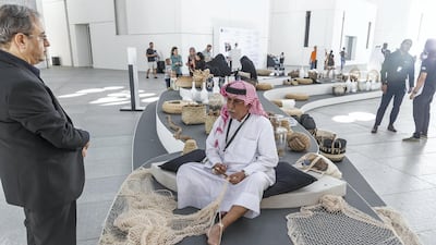 An Emirati man shows visitors traditional weaving techniques for fishnets during a UAE National Day Program at Louvre Abu Dhabi in December 2018. Antonie Robertson / The National