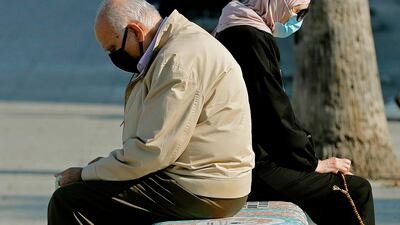 A man and a woman sit back-to-back on a bench as they enjoy a sunny day near the Beirut seaside promenade. AFP