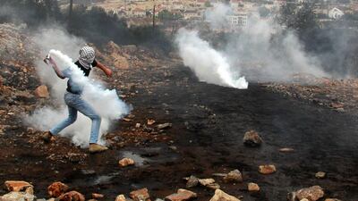 A Palestinian protester throws back an Israeli tear-gas canister following a demonstration against the expropriation of Palestinian land by Israel on Friday in the village of Kfar Qaddum in the West Bank. Jaafar Ashtiyeh / AFP