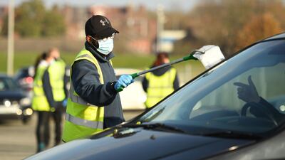 A worker speaks to a member of the public arriving by car at a testing facility in Liverpool. AFP