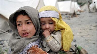 A girl carries her brother at a camp at Azharabad near Gilgit. People living on the banks of the Hunza River have been evacuated to nearby relief camps, bottom, to protect them from the threat of flash floods. Below, government officials visit the affected region.