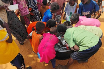 Sudanese children scrape leftover food from a pot in Al Rahmaniyah camp. AFP