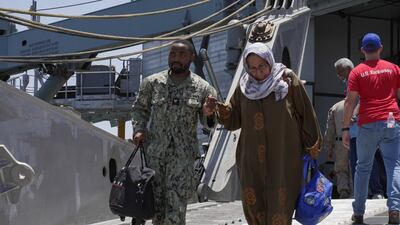 An US Navy serviceman helps a woman disembark from the USNS Brunswick after its arrival in Jeddah, Saudi Arabia. Reuters