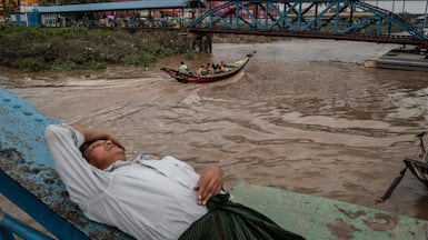 A man rests as a boat carrying passengers powers through the waters of the Yangon River in Yangon, Myanmar. AFP