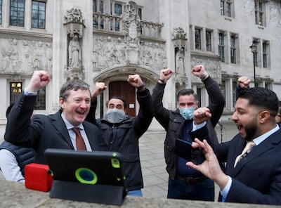 Uber drivers of the App Drivers & Couriers Union celebrate as they listen to the court decision on a tablet computer outside the Supreme Court in London. AP Photo