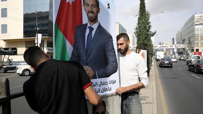 Men hang a poster of one of the candidates, ahead of parliamentary elections which will be held on November 10, amid fears over rising number of the coronavirus disease cases, in Amman. Reuters