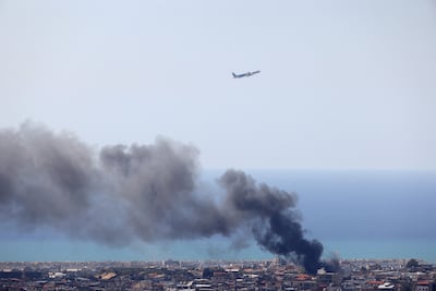 An aircraft takes off in Beirut as smoke rises from the site of an Israeli air strike in March. AFP
