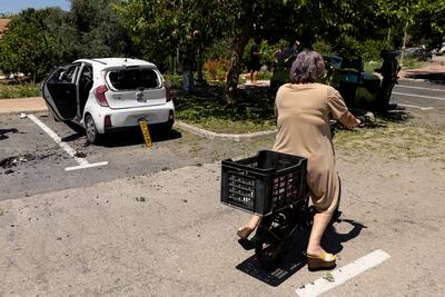 A Kibbutz member passes by a car that was damaged in a drone attack in the Galilee region of Israel. Getty Images