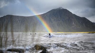 Surfer Anker Olsen Frantzen rides a wave under a rainbow during a free surf session in Flakstad, Norway. Olivier Morin/AFP