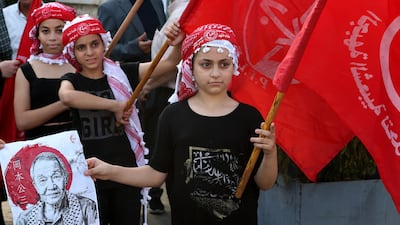 Children carry posters of Okamoto during the funeral procession