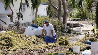 A man shovels seagrass from the entrance of his mobile home in the wake of hurricane Irma at Tavenier Key, Florida. Gaston De Cardenas / AFP