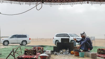 Abu Dhabi, United Arab Emirates, December 11, 2019. Hamed Al Merri warms himself by the fireside at his family's tent in the dunes of Al Dhafra. Victor Besa / The National Section: NA Reporter: Anna Zacharias