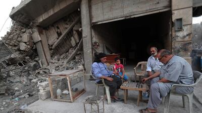 Syrian men play chess outside a shop next to a cage of pigeons in the rebel-held town of Maaret al-Numan, in the north of Idlib province on September 2. AFP