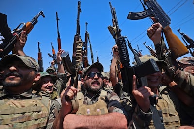 Iraqi militants wave their weapons in Samarra. The war has drawn in countries such as Iraq with pro-Iran armed factions. AFP