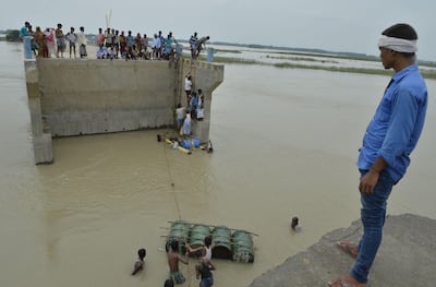 Indian villagers use a raft made of empty oil barrels to cross a washed away section of a bridge at Palsa village in Purnia district of Bihar state on August 18, 2017. Diptendu Dutta / AFP