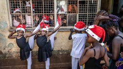 TOPSHOT - Young ballet students warm up with stretching exercises before taking the stage during Project Elimu’s annual Christmas ballet performance in the Kibera informal settlement of Nairobi, on December 23, 2025. At Project Elimu’s Kibera Ballet School in Nairobi, young dancers engage with classical ballet as part of a community-led arts programme that fosters discipline, creativity and confidence. Founded by Kenyan dancer Mike Wamaya, the free classes form part of a wider initiative supporting artistic expression, learning and personal growth. (Photo by Luis TATO / AFP)
