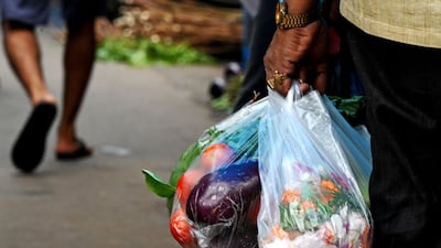 A man carries flowers and vegetables in single-use plastic bags at a local market in Kolkata. AFP