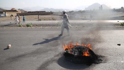 People walk past a burning tyre after a suicide bomb hit an election rally in Nangarhar province, Afghanistan. EPA
