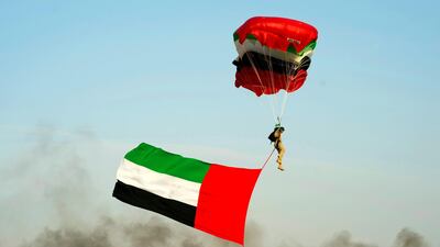 A solider parachutes down carrying the UAE flag. Wam