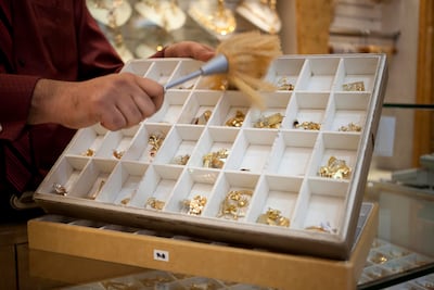 A salesman dusts gold jewelry at the Gold Souk in Deira, Dubai. Razan Alzayani / The National