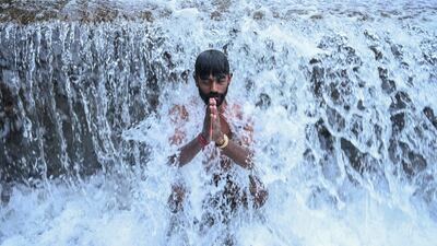 TOPSHOT - A devotee takes a holy dip in the Bagmati River before offering prayers to the Hindu god Shiva at the Pashupatinath Temple during Shravan festivities on the outskirts of Kathmandu on August 4, 2025. (Photo by Prakash MATHEMA / AFP)