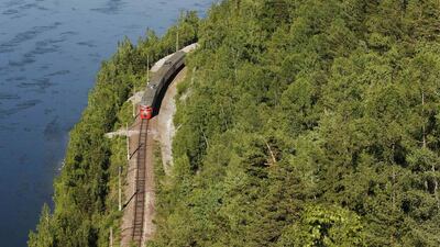 A passenger train moves along a railway along the bank of the Yenisei River near the village of Sliznevo. Ilya Naymushin / Reuters