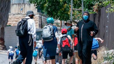 A Palestinian woman walks past a group of Israeli settlers as she walks home on al-Shuhada street in the H2 area of the city of Hebron, in the occupied West Bank. AFP