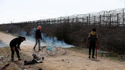 Migrants try to cut the fence at the Turkish-Greek border. AP