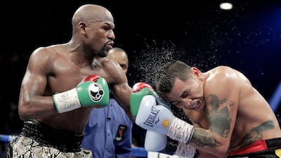 Floyd Mayweather hits Marcos Maidana with a left hand during their title fight on Saturday. John Gurzinski / AFP