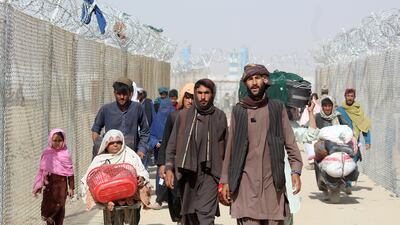 Afghan people walk inside a fenced corridor as they enter Pakistan at the Pakistan-Afghanistan border crossing point in Chaman. AFP