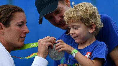 Switzerland’s Nicola Spirig (L) shows her silver medal to her family after the women’s triathlon at Fort Copacabana during the Rio 2016 Olympic Games in Rio de Janeiro on August 20, 2016. Leon Neal / AFP