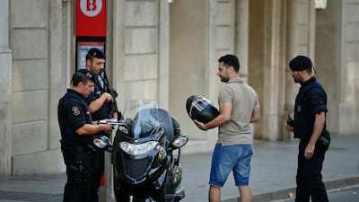 Armed police officers check a man's identity on a street near Las Ramblas. Manu Fernandez / AP Photo