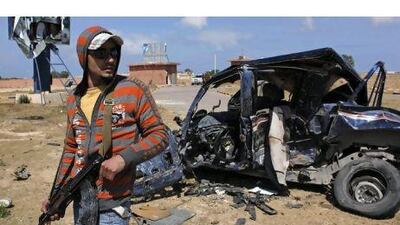 A rebel fighter stands guard near a destroyed vehicle on the outskirts of Brega, Libya, yesterday.