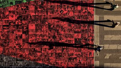 People walk next to a Palestinian flag made of photographs of dead civilians, displayed on a street in Sarajevo, Bosnia. AP Photo