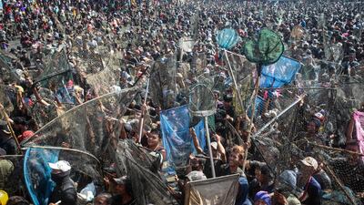 People try to catch about two tonnes of fish released by the city during an annual event to thank locals for the fishing harvest at Gemblegan Reservoir in Klaten, central Java. AFP