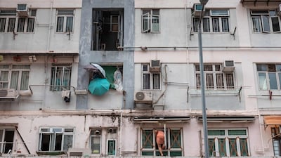 A woman climbs back into her apartment in Hong Kong after taping the windows as Super Typhoon Ragasa approaches. AFP