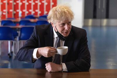 Britain's Prime Minister Boris Johnson holds a cup of coffee as he speaks to pupils after taking part in a science lesson at King Solomon Academy in London. AFP