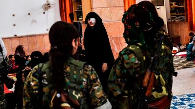 A Syrian woman looks at fighters from the Syrian Democratic Forces as civilians gather on the western front after fleeing the centre of Raqqa on October 12, 2017. Bulent Kilic / AFP