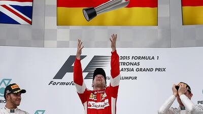 Vettel, centre, jumps throwing the trophy to the air next to second placed Lewis Hamilton, left, and third place Nico Rosberg. Fazry Ismail / EPA