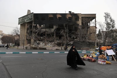 A woman passes the burnt-out shell of a state tax building in Tehran that was destroyed during Iran's anti-government protests. Reuters