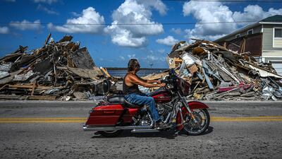 A motorcyclist rides past debris piled up from a destroyed home after the passage of Hurricane Ian on Matlacha Island in Lee County, Florida. AFP