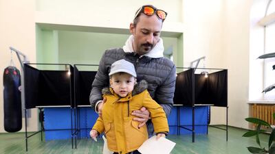 A voter with a child prepares to cast his ballot. AFP