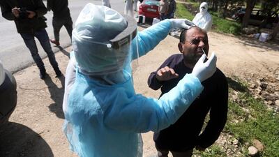 An employee of the Palestinian health ministry collects a swab sample from a worker crossing back from Israel at the checkpoint of Tarqumiya, near the West Bank town of Hebron. EPA