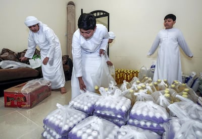 Mona Mohammed's sons help sort out food supplies to be distributed to those in need. Victor Besa/The National